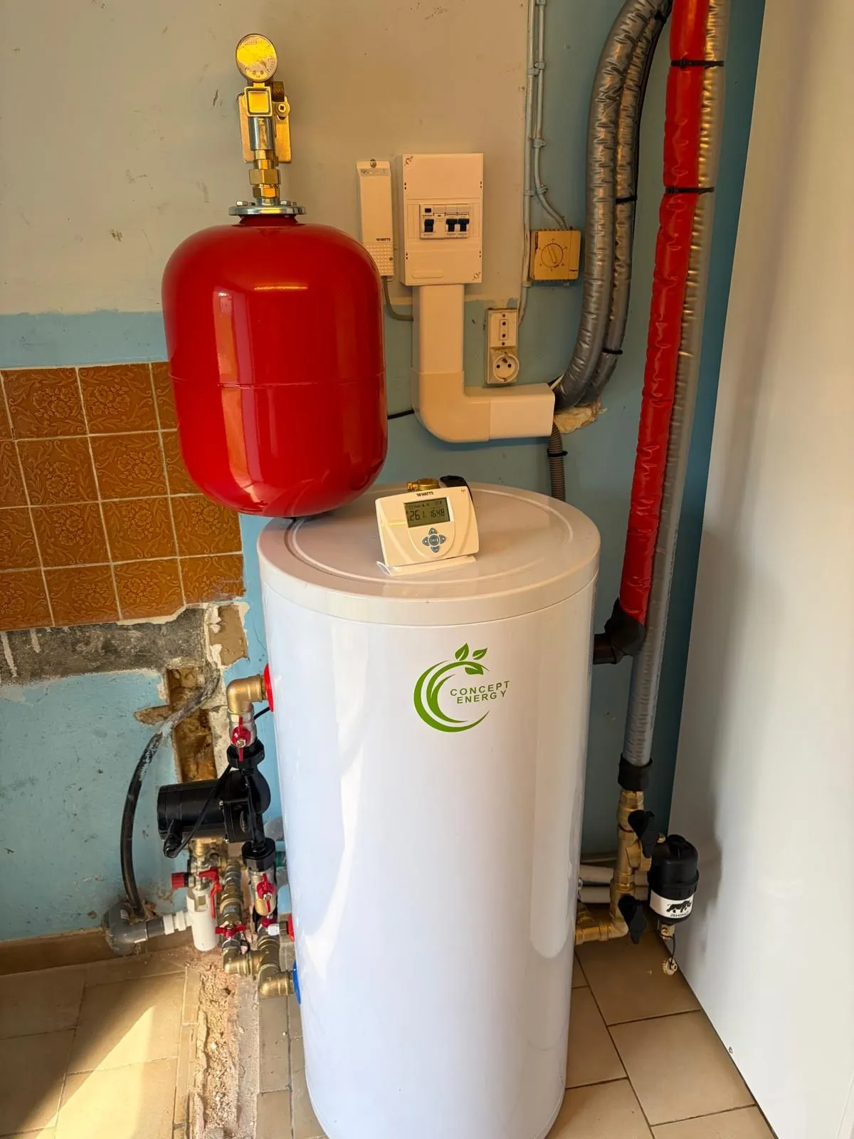 Ballon d’eau chaude et vase d’expansion sanitaire rouge installés le long d’un mur